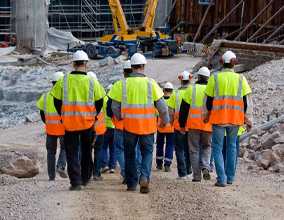 Workers in safety gear on a construction site with tower cranes
